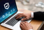 Homem de negócios usando laptop, com uma tela de proteção que representa o sistema antifraude para e-commerce.