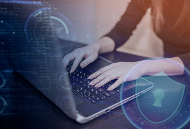 Imagem de uma técnica de TI usando notebook, com símbolos digitais representando a cibersegurança para empresas.