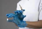 Profissional de saúde segurando um frasco e uma seringa, representando a importação de medicamentos