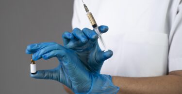 Profissional de saúde segurando um frasco e uma seringa, representando a importação de medicamentos