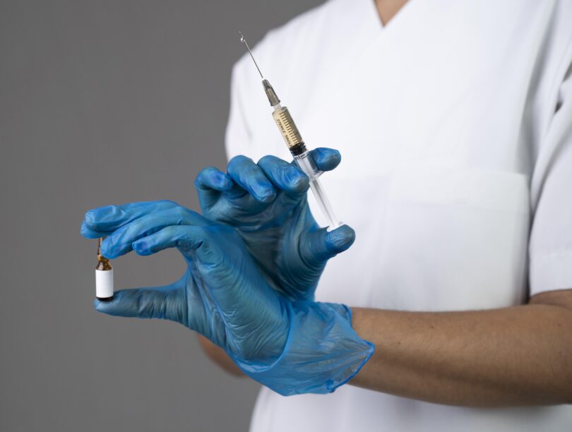 Profissional de saúde segurando um frasco e uma seringa, representando a importação de medicamentos